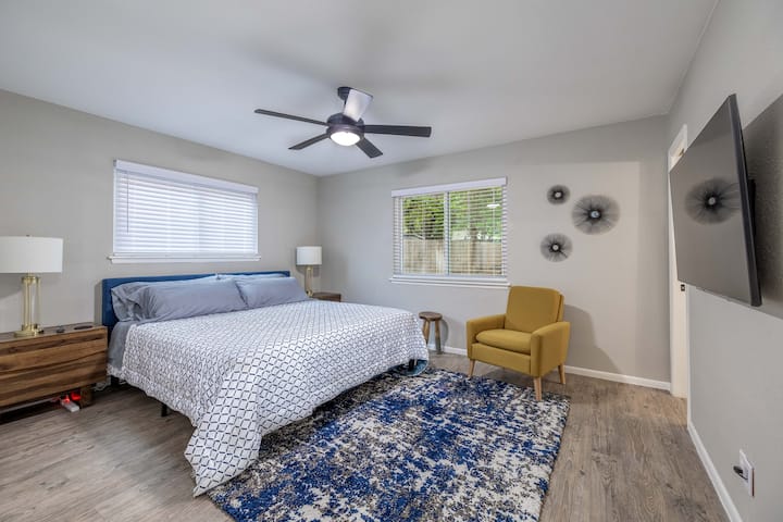 Maravilloso dormitorio principal con ventilador de techo, mesas laterales, una zona de estar y un nuevo televisor inteligente. 