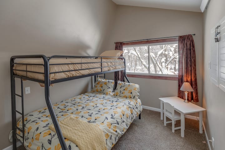 Upper bedroom with twin over full bunk beds and a kids desk.