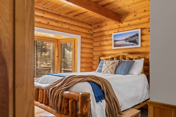 First floor bedroom features a queen size bed on a natural log frame with a bay window and window seat