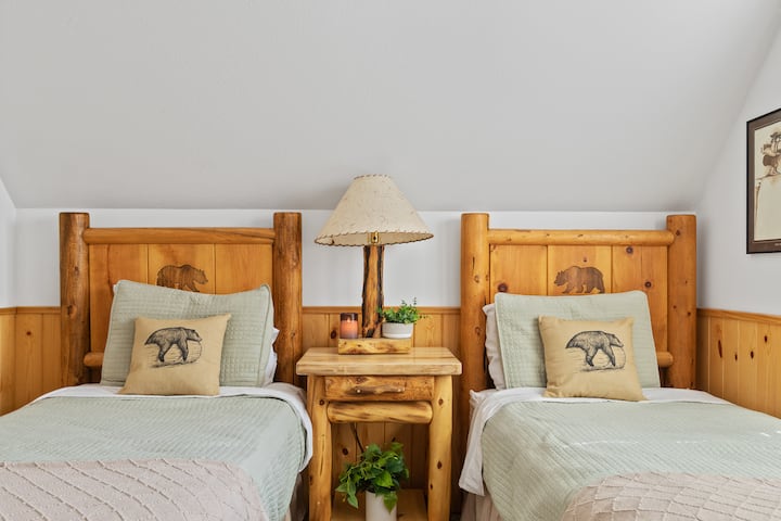 Third bedroom featuring natural log furniture with a nightstand and lamp between the two twin beds