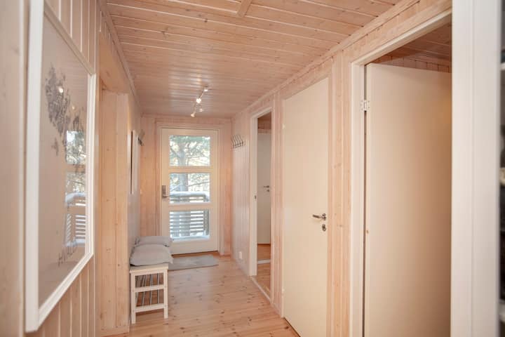 Ufikiaji wa chumba cha kulala unaonekana kutoka kwenye mlango wa nyuma hadi kwenye mlango wa mbele. Benchi dogo lenye mito na chumba cha viatu pamoja na kinyoosha nywele pande zote mbili za ukumbi hutoa nafasi ya kuvua nguo za nje na viatu njiani kuingia. Picha: Mette Randem