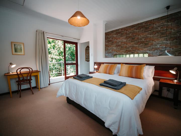 ห้องนอนชั้นบนพร้อมเตียงขนาดควีนไซส์และระเบียงขนาดเล็ก