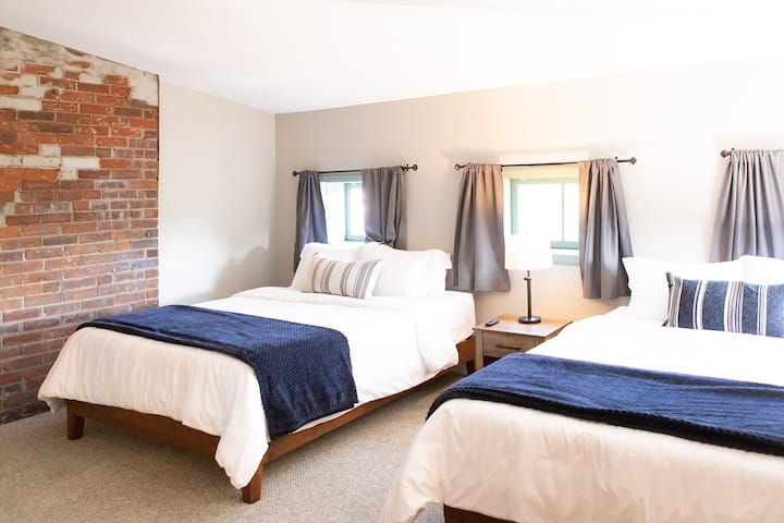 Dormitorio de invitados con dos camas matrimonial y un televisor Roku. 