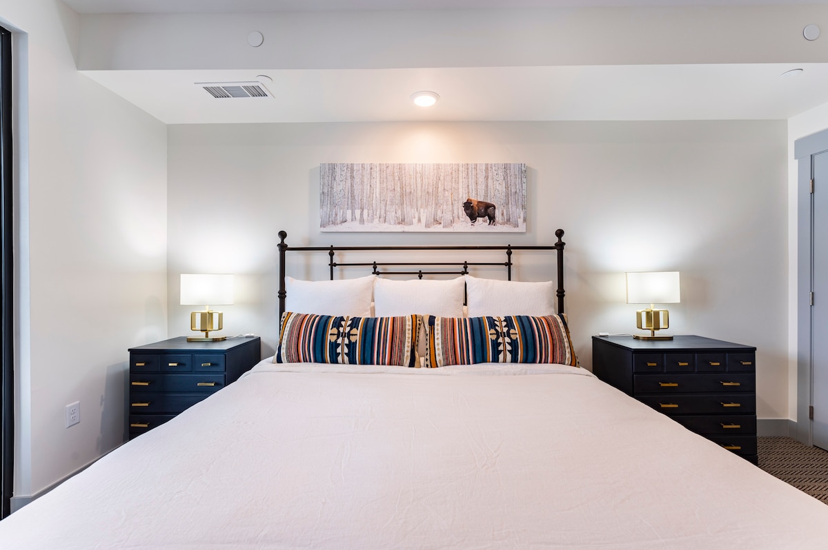 Glavna spavaća soba s bračnim krevetom i kliznim staklenim vratima koja vode na terasu.  