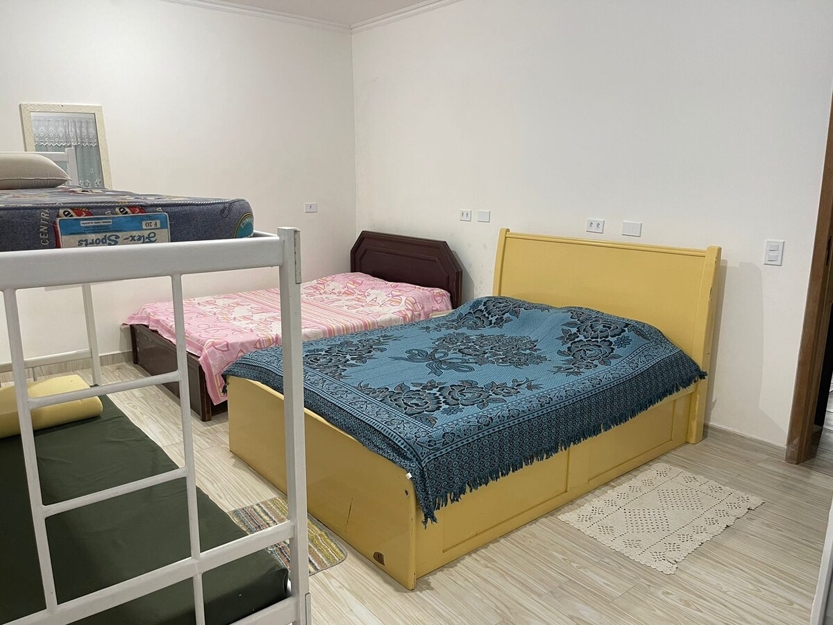 Suite 01: 02 camas dobles + 01 litera. Ventana con persianas, pantalla y cortina integradas. Está en la planta baja, frente a la piscina. Tiene acceso tanto dentro de la casa como en el área de la piscina.