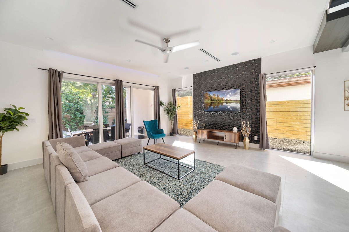 Salon spacieux avec un grand canapé sectionnel, une décoration moderne et une télévision connectée : idéal pour se détendre ou se retrouver en groupe