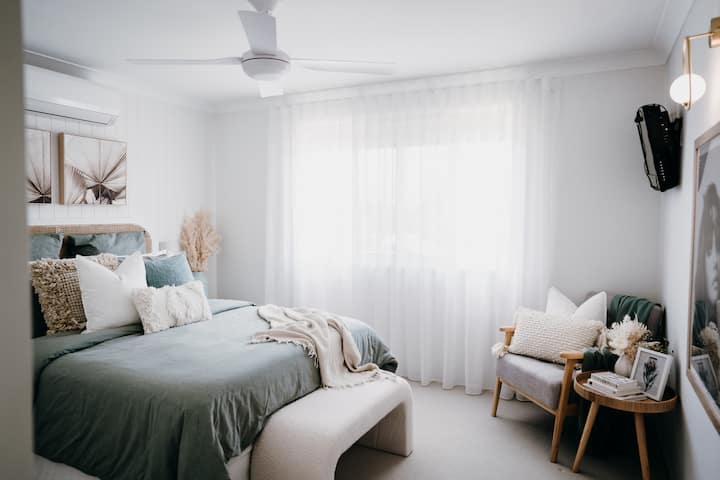 Master Bedroom features, queen bed with extra plush pocket spring mattress with rattan bedhead. Room also features, wall mounted smart TV