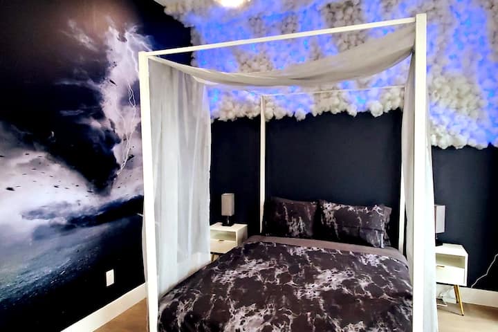 Chumba cha kulala chenye mandhari ya kuvutia kilicho na kitanda cha dari chenye starehe, mwanga laini na sanaa ya ukutani inayovutia, kinafaa kwa mapumziko ya kustarehesha