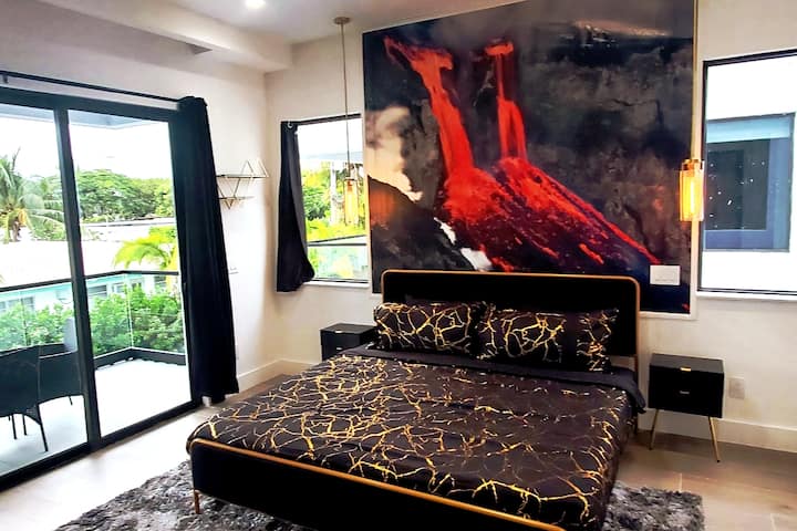 Chumba cha kulala chenye mtindo na kitanda cha mfalme, sanaa ya ujasiri, mwanga wa asili na ufikiaji wa roshani binafsi.