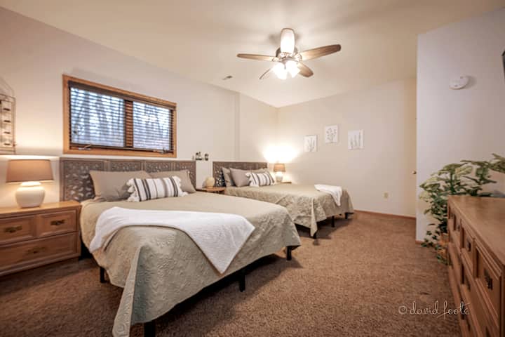 ห้องนอนพร้อมเตียงควีนไซส์ 2 หลังและสมาร์ททีวีขนาด 65 นิ้วอยู่ชั้นล่าง