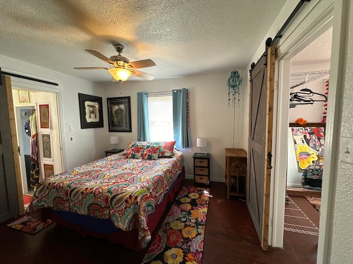 חדר שינה אמצעי עם מיטת קווין סייז וחדר רחצה צמוד.