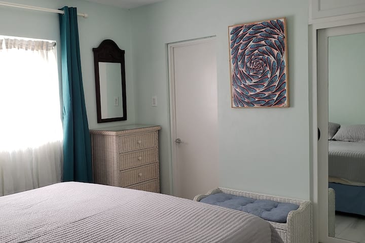 Dormitorio principal con baño privado: cama tamaño king, aire acondicionado, 2 cómodas y un banco, armario con amplio espacio de almacenamiento.