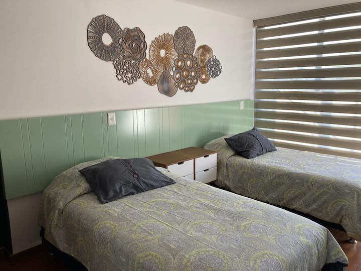 Spavaća soba s dva kreveta za jednu osobu, kupaonicom, pergolama, ormarom i namještajem za pohranu te izlazom na vanjski balkon 