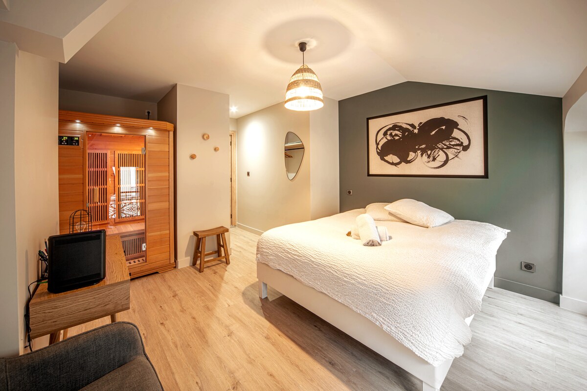 Seconde chambre avec un sauna deux personnes lit double draps doux fauteuil et décoration soignée 