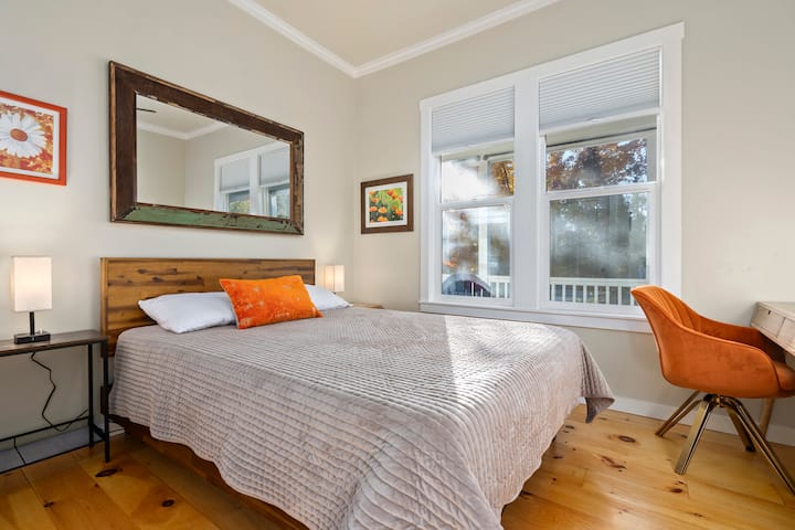 El dormitorio n.º2 cuenta con una cama tamaño queen, cortinas opacas, obras de arte locales y un escritorio y una silla que son una configuración perfecta para el trabajo a distancia.