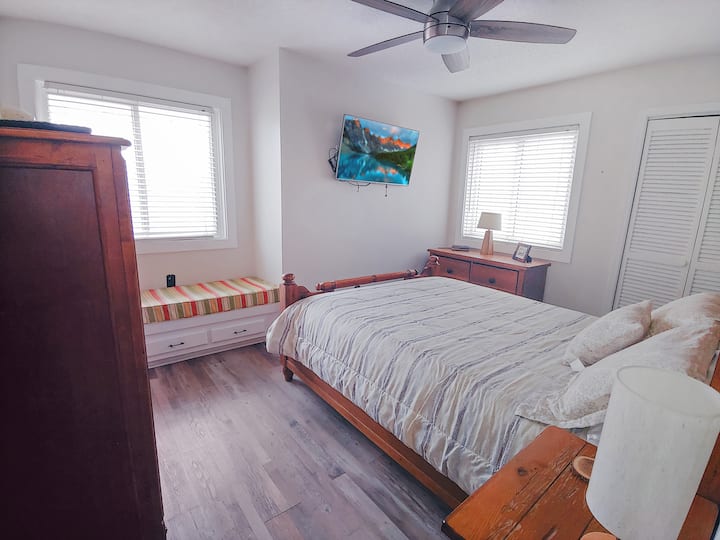 Master bedroom with attached bathroom, Queen bed, ceiling fan, TV, closet, dresser