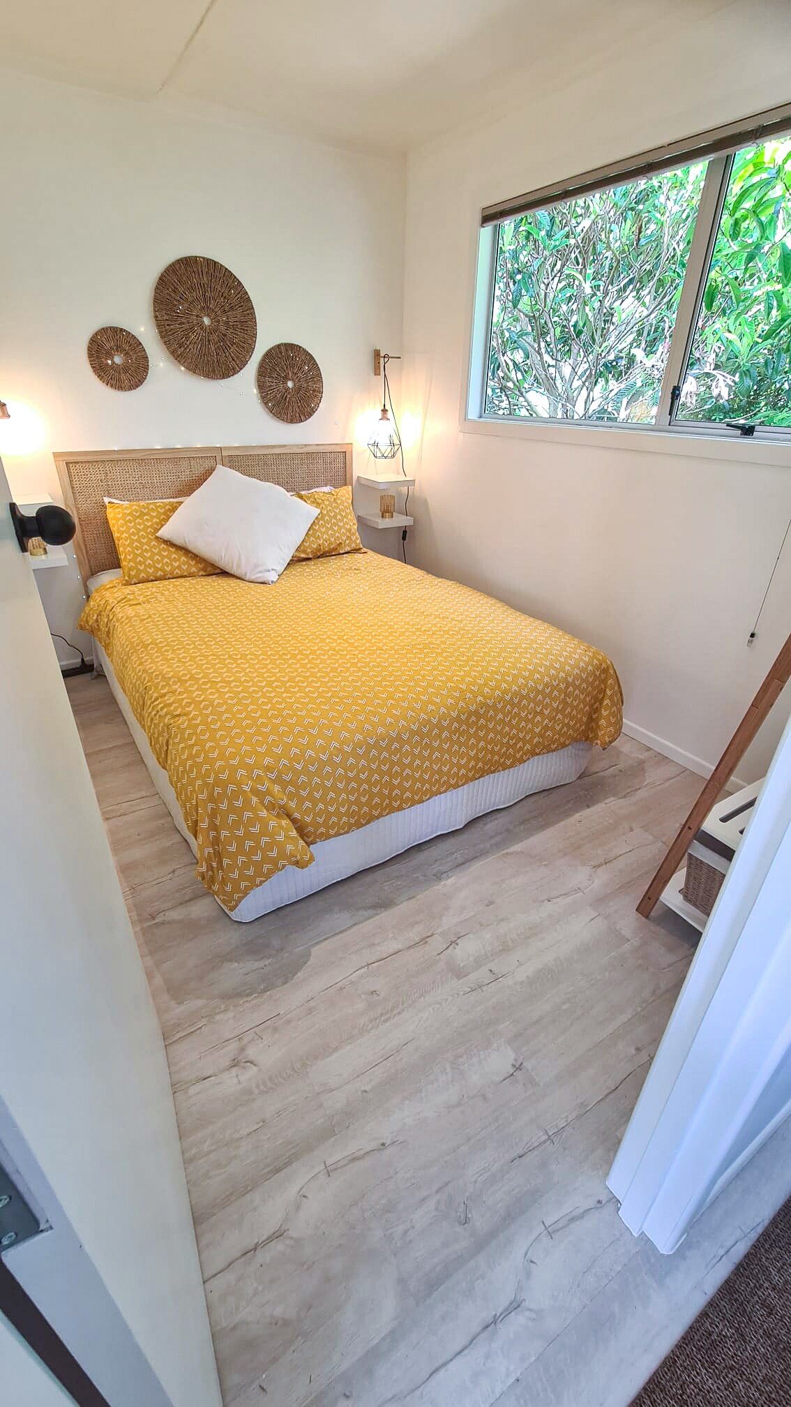 The second bedroom enjoys a queen size bed, table lamps, a clothes storage rack, a full-length dressing mirror and side tables.