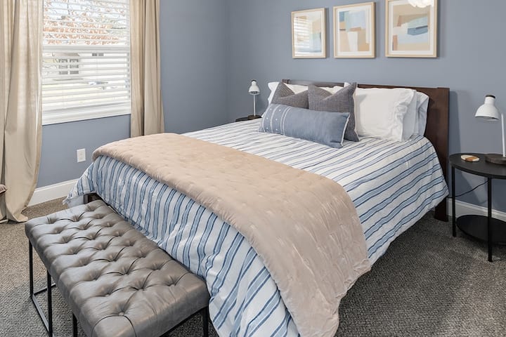 Bedroom #3 with a Queen bed. Bedroom has a Roku television, lounge chair and luggage rack.