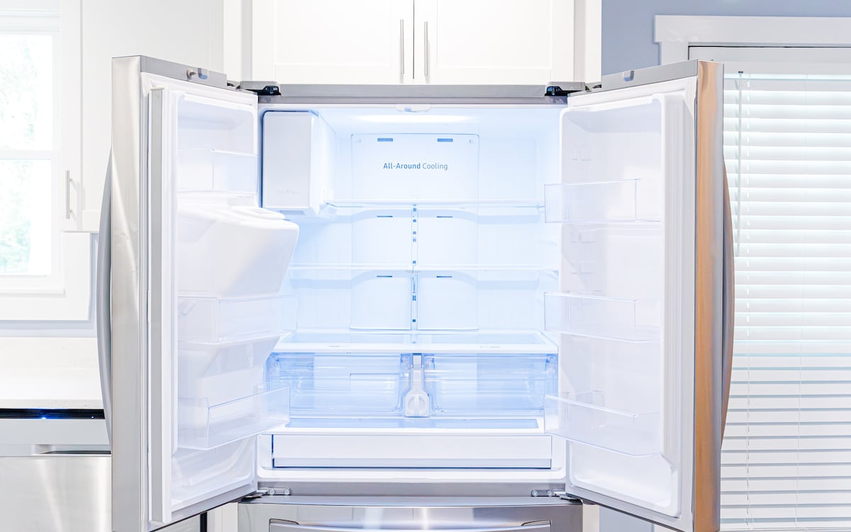 A modern refrigerator with stainless steel finish is shown with both doors wide open, revealing a spacious interior. Bright LED lighting illuminates the empty shelves, which are designed for versatile storage options. The clean lines and sleek design emphasize its contemporary functionality.