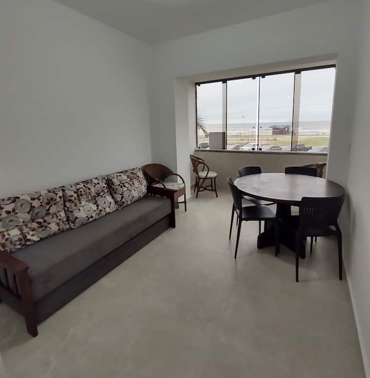 סלון עם טלוויזיה חכמה, שולחן אוכל ונוף לחוף.