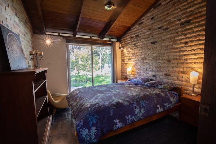 Bedroom 3 has a queen double, a sitting chair and views across the front garden and pond.