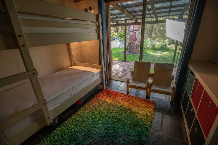 The kids' bedroom looks out onto the verandah and back garden. There are bunks, plenty of storage and chairs they can take out into the garden. For safety's sake, the sliding door is locked, so the kids have to go through the kitchen to go outside.