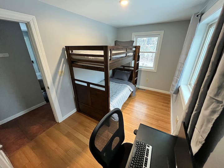 أسرّة بطابقين ومساحة عمل مكتبية مع مكتب وشاشة.