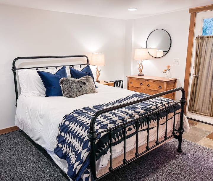 Main floor bedroom features a queen bed,  43” TV, dresser and direct access to the backyard.