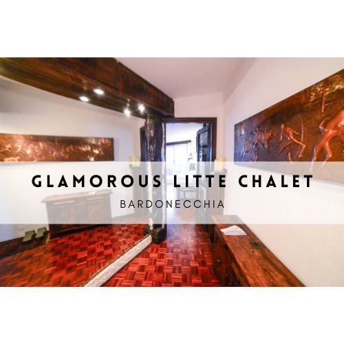 The entrance area features a wooden design with decorative wall panels. A spacious mirror reflects a handmade copper artifact, enhancing the rustic charm. A rich oak parquet floor extends throughout the area, contributing to the warm ambiance of the chalet.