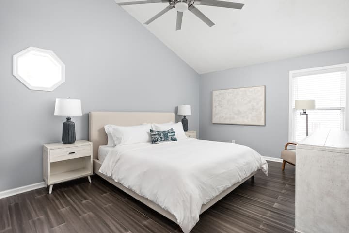 Master bedroom with king bed, reading chair, and 55" smart TV.
