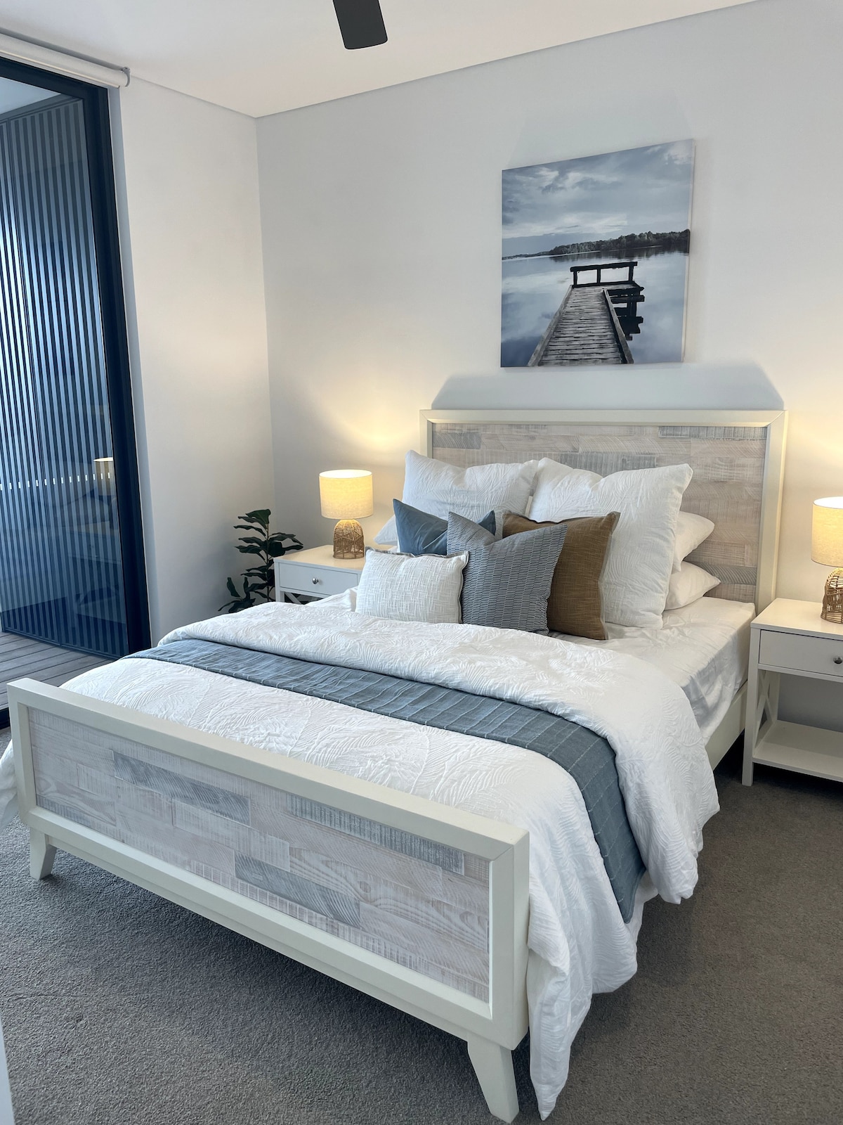 Chambre principale avec armoire intégrée, ventilateur au plafond, salle de bain attenante et stores d'appoint pour le confort du couchage. 