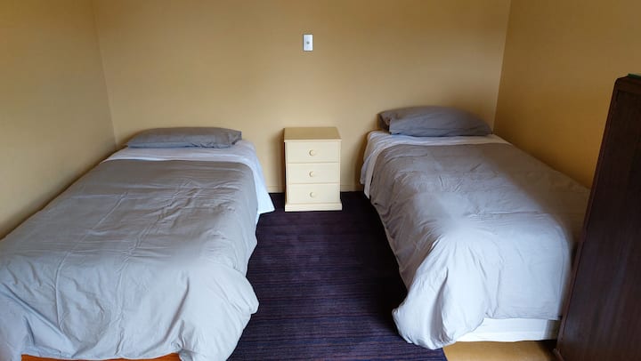 La habitación de abajo tiene dos camas individuales, un albornoz y dos ventanas de esquina al pie de las camas ...