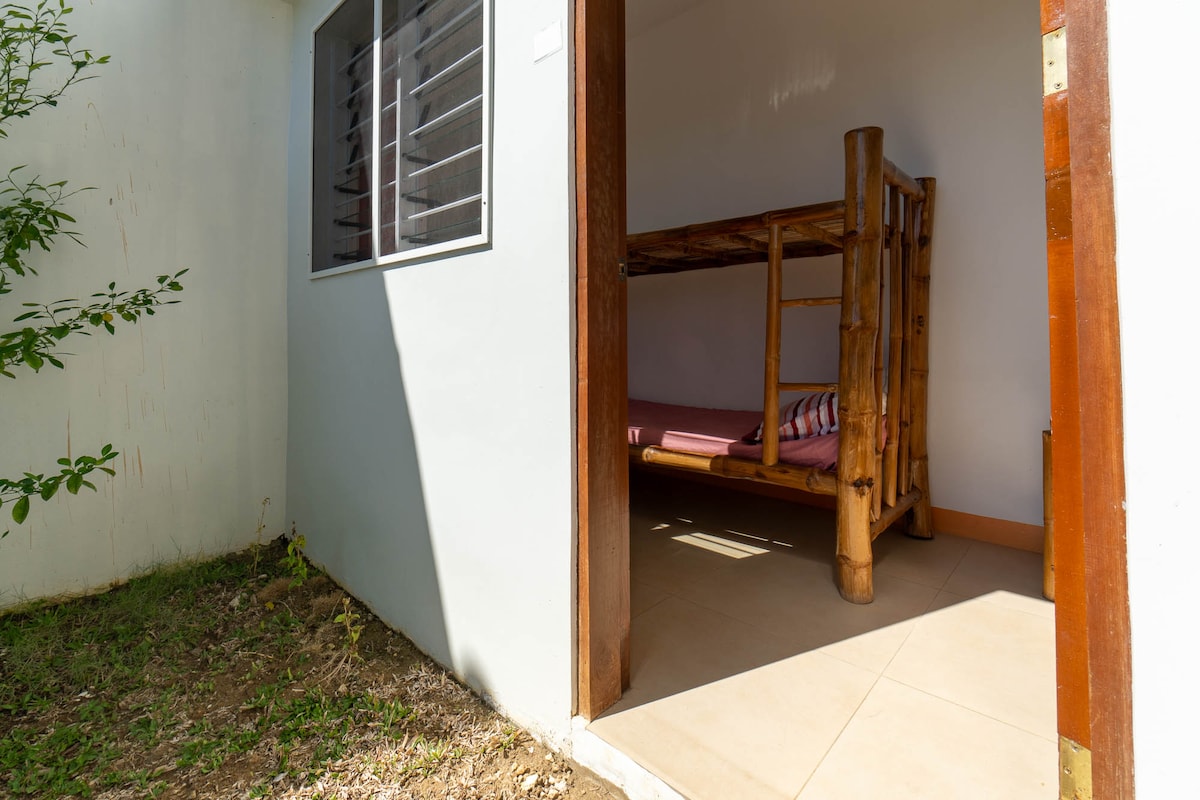 La habitación sin aire acondicionado con litera y ventilador de techo. El inodoro y las instalaciones de baño están debajo de las escaleras en el acceso del piso. 