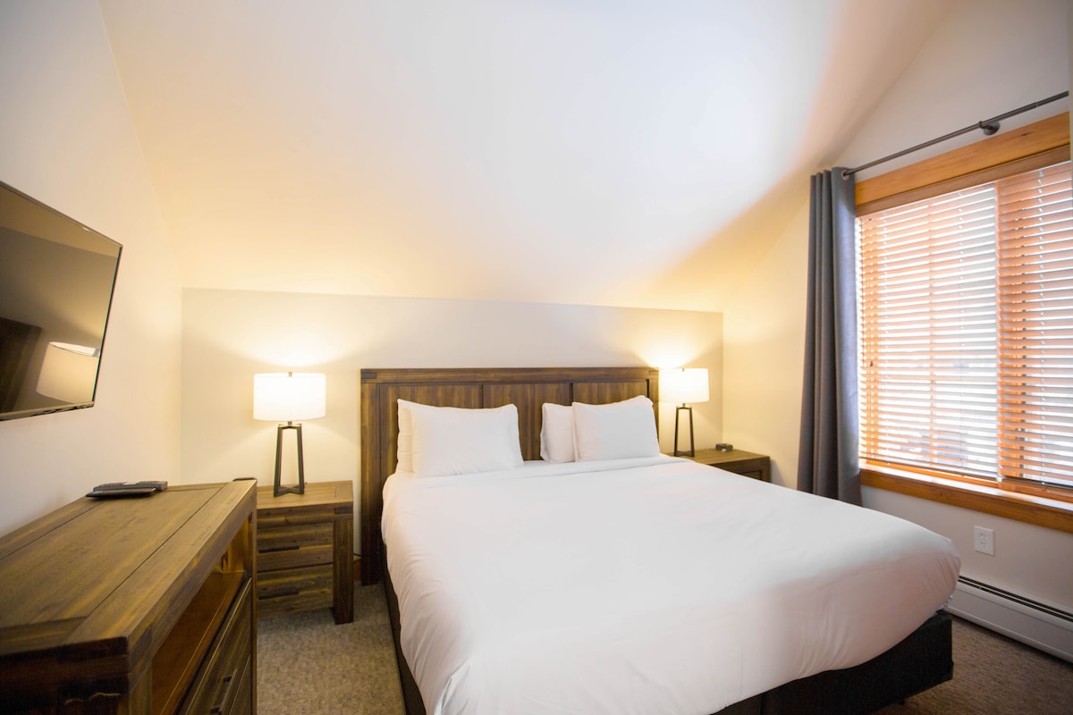 Dormitorio principal con cómoda cama tamaño king, cortinas opacas, despertador y puertos de carga USB. 