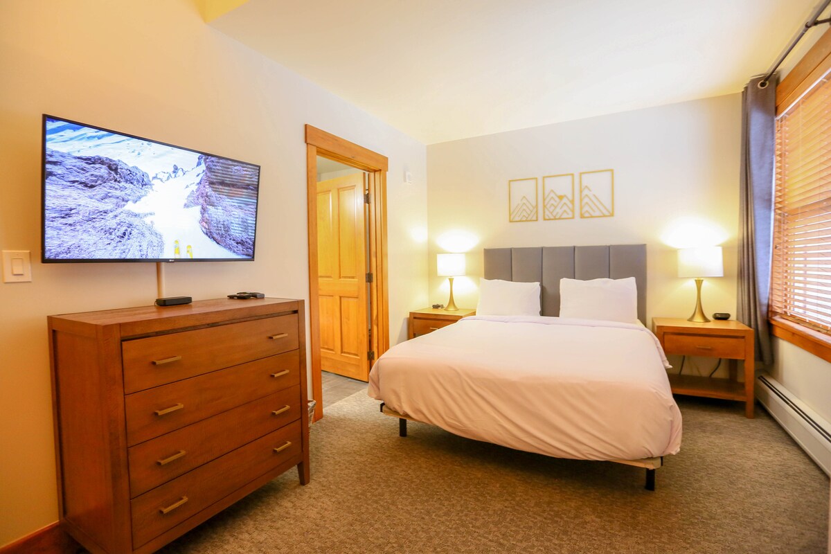 Segundo dormitorio con cortinas opacas, reloj despertador y puertos de carga USB. 