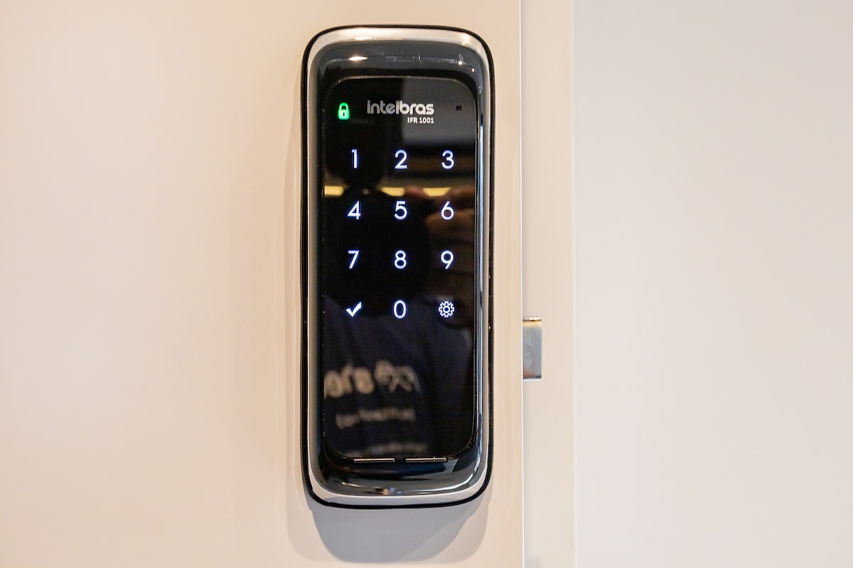 A digital keypad lock is mounted on a wall, featuring a glossy surface with illuminated numeric keys. An icon indicating a secure lock is displayed, along with a unique code entry interface.