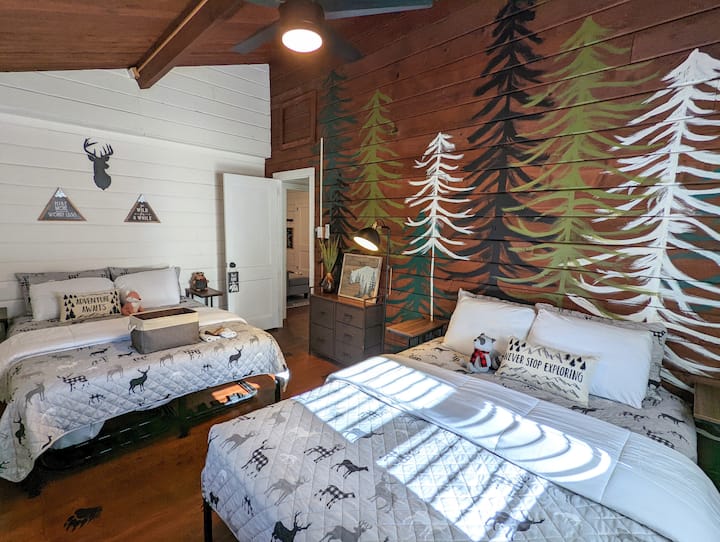 Bedroom 2 -“The Mountain Room” with 2 queen beds, storage, and minisplit unit. Mountain scape wall hand painted by owner! Be sure to look for the bear tracks! Bedrooms located next to each other at back of house.