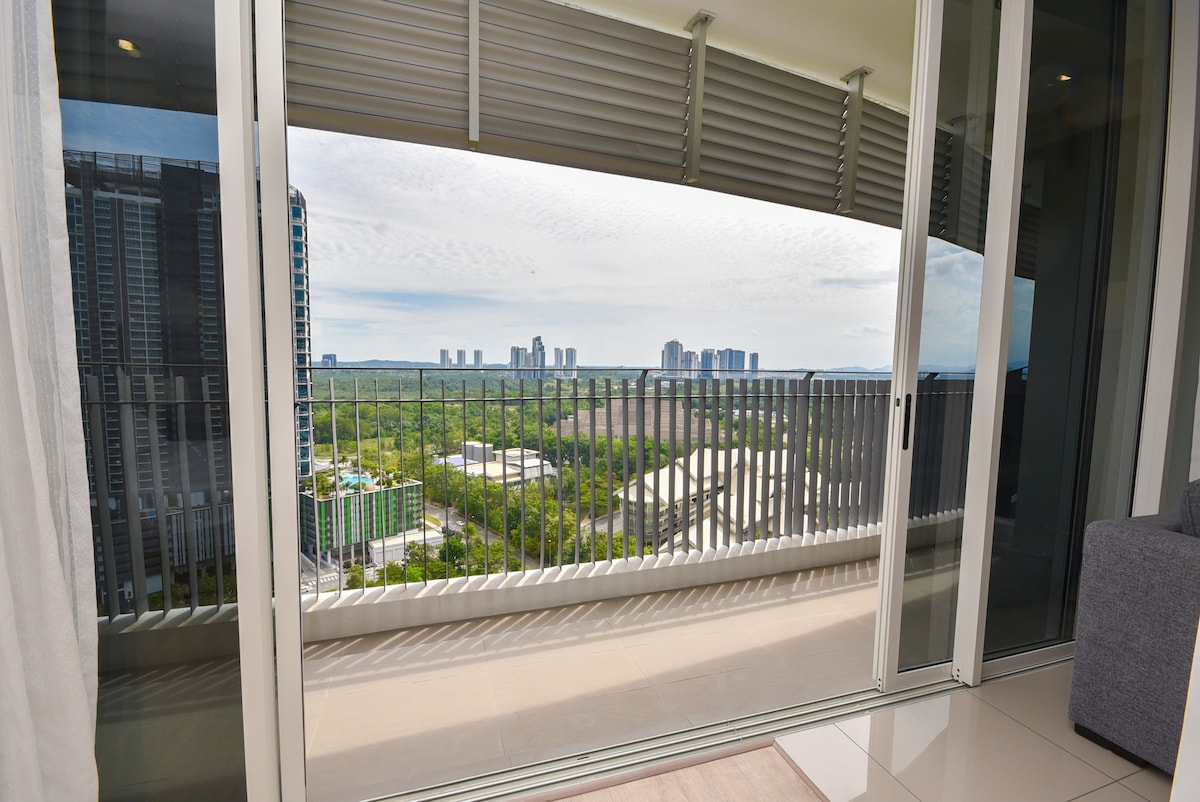 A balcony view showcases a panoramic landscape, with rolling green fields and distant city buildings under a cloudy sky. The glass doors provide a seamless transition between indoor and outdoor spaces, allowing natural light to brighten the interior area.