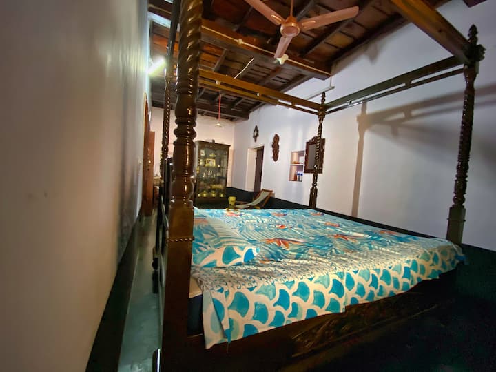 Dormitorio principal con aire acondicionado que muestra una cama con dosel con una cómoda silla de tela y una caja de vidrio antiguo que muestra antigüedades