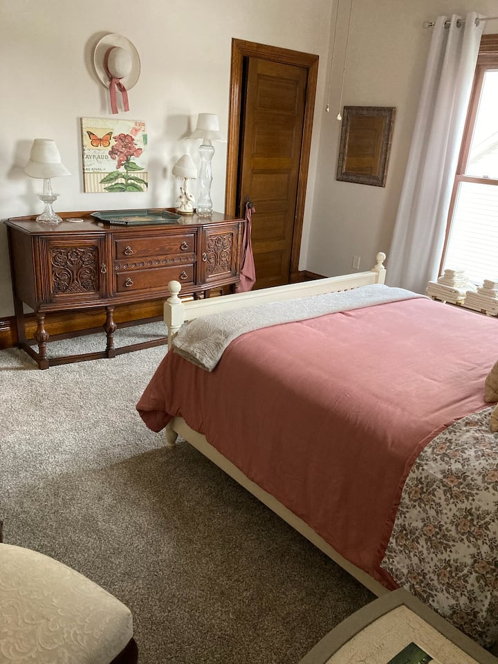 This upstairs queen bedroom has a bright airy feel, with its carved oak buffet and soft bedding.