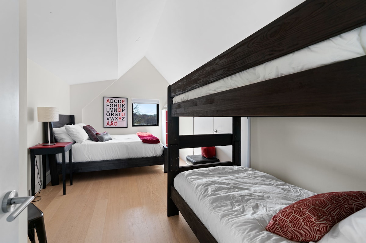 The third-story guest room features a large open space, with queen bed and two bunk beds. 