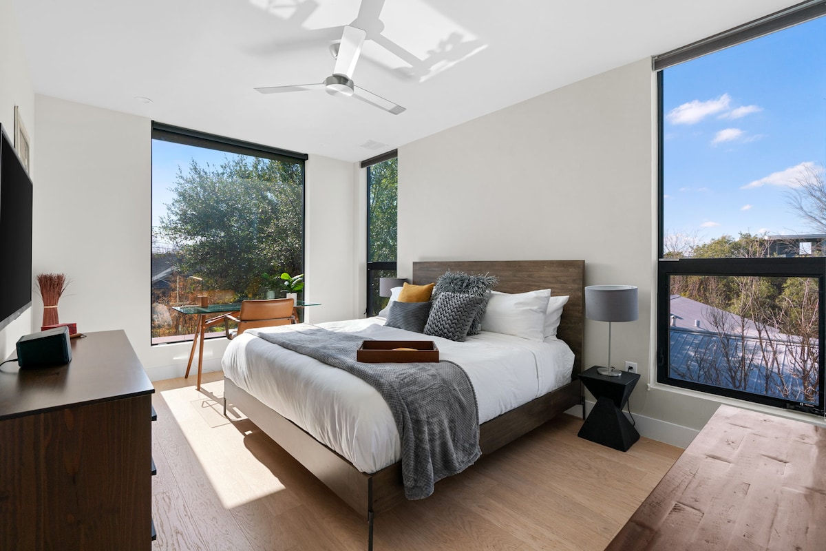 The luxurious master bedroom features lots of light with electronic blackout shades, a workspace and a 55 inch TV.