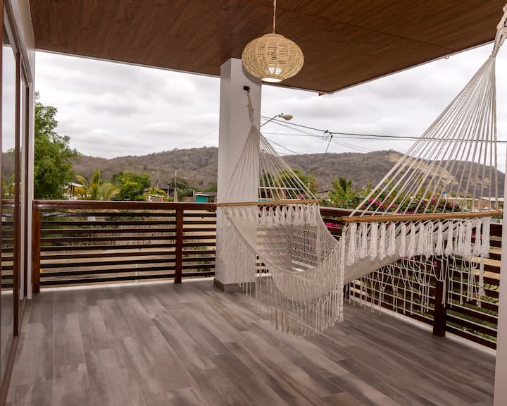 Balcón del segundo piso en Orion Lodge. Contamos con una amaca, para que pueda relajarse mientras lee un libro o descansa. Vista directa a la playa los Ciriales. Las luces del balcón y áreas externas en el segundo piso se encuentran automatizadas.