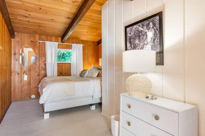 Bedroom #1. This room looks out a lush forested view and has a Full size memory foam bed, dresser, 2 clothes hanging options, and USB charging ports in both nightstands. 