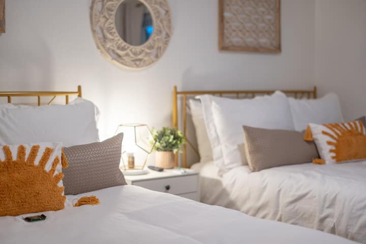 غرفة نزلاء تضم سريرين كاملين مجهزين ببياضات أسرة فاخرة ومزينة بشكل عصري بإضاءة حضرية. 