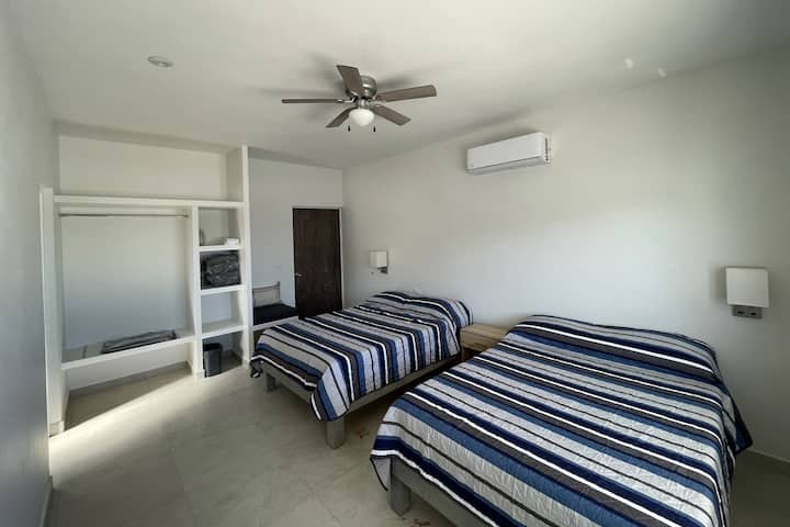 Velika spavaća soba u prizemlju s kupaonicom s WC-om i dva bračna kreveta te pogledom na bazen.