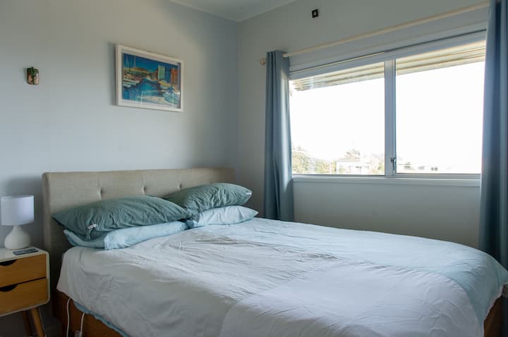Front bedroom with x1 Queen bed. Lovely to sit up in bed and enjoy the view of Kapiti Island in the morning, open the window and hear the sea lapping on the beach. There is a TV on the wall if you enjoy laying in bed catching a movie.