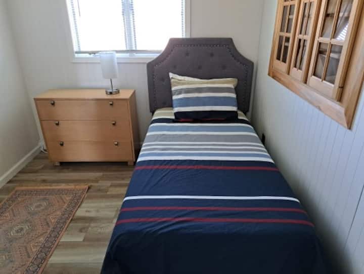 The single bedroom includes a dresser as well as a clothes rack. 