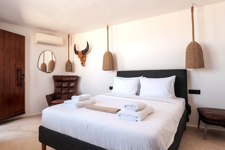 "Unwind in our Mykonos villa's luxurious bedroom with ensuite bathroom. Create unforgettable moments of relaxation and bliss in this oasis of comfort and indulgence."