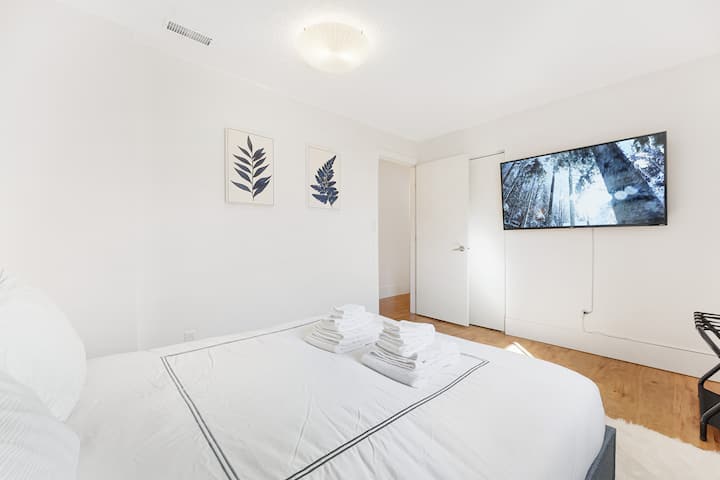 "Experience Comfort and Entertainment in Our Queen Bedroom with a 55-inch TV, Streaming Services, Beautiful Artwork, and Convenient Touch Lamps with USB Charging. Stay Organized with Our Luggage Rack and Relax in Style."